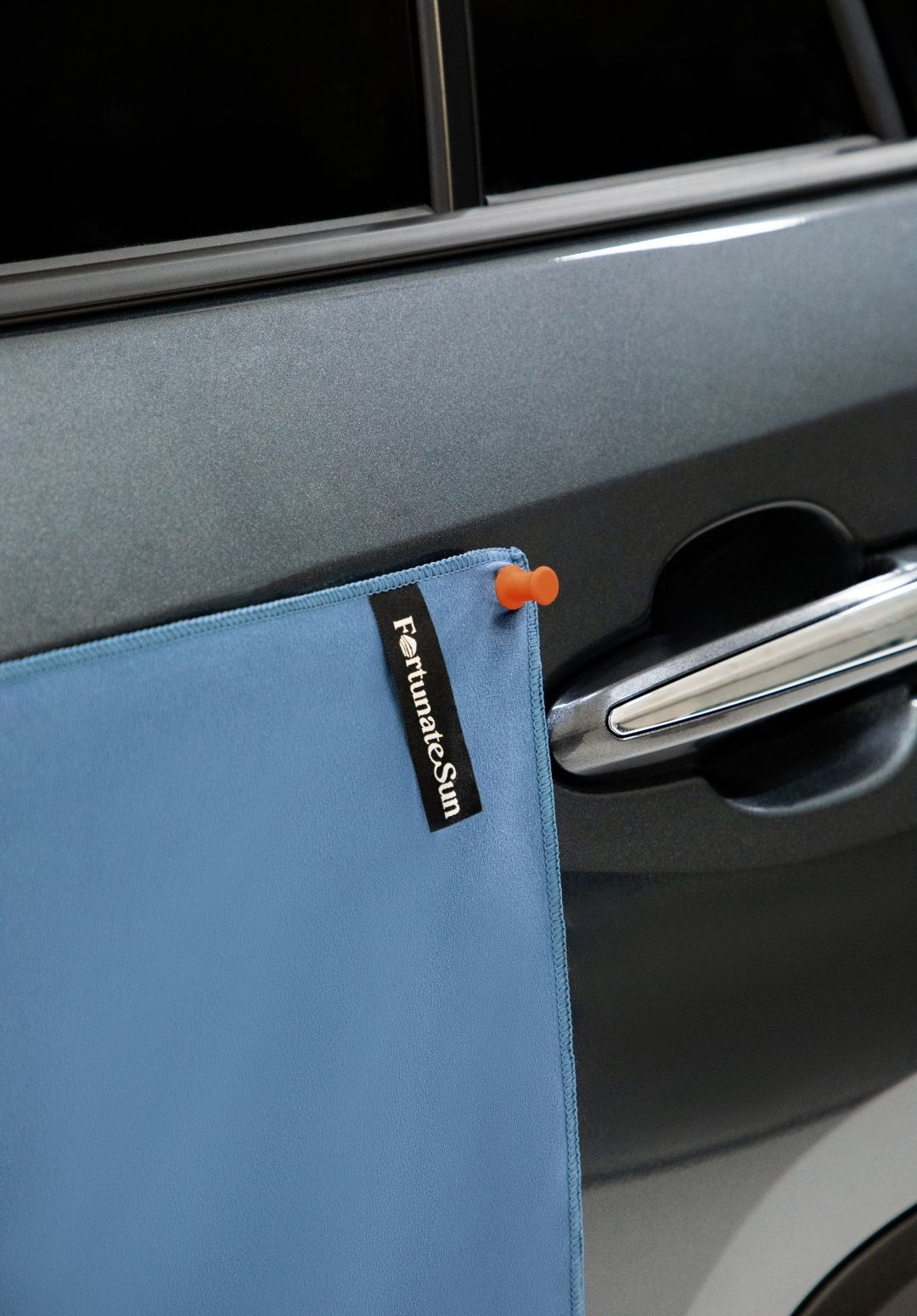 Fortunate Sun Hidey towel being hung up on car exterior using their magnets.
