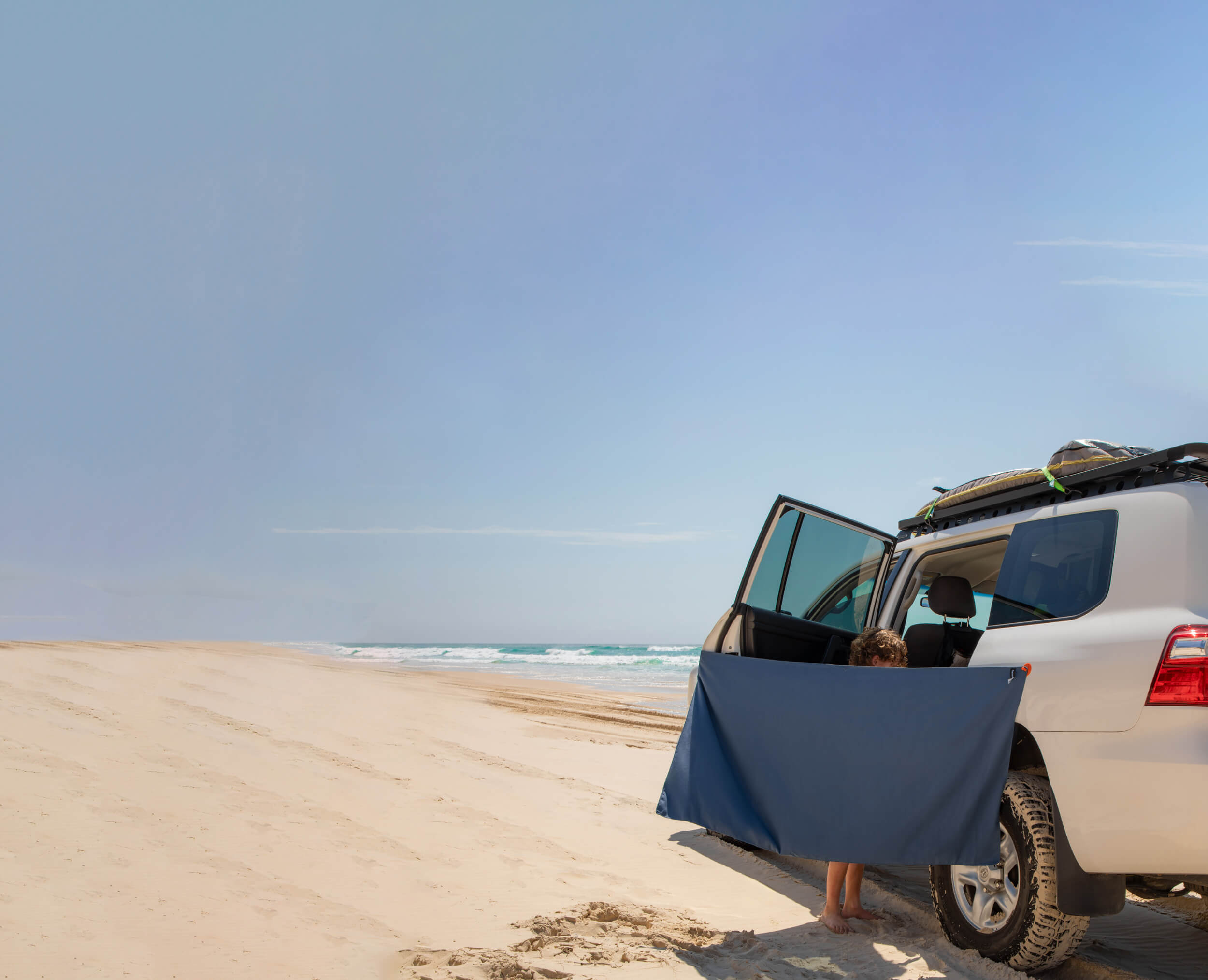 Toyota Landcruiser car on an Australian beach with a kid using the Fortunate Sun Magnet and Suction Towel called Hidey