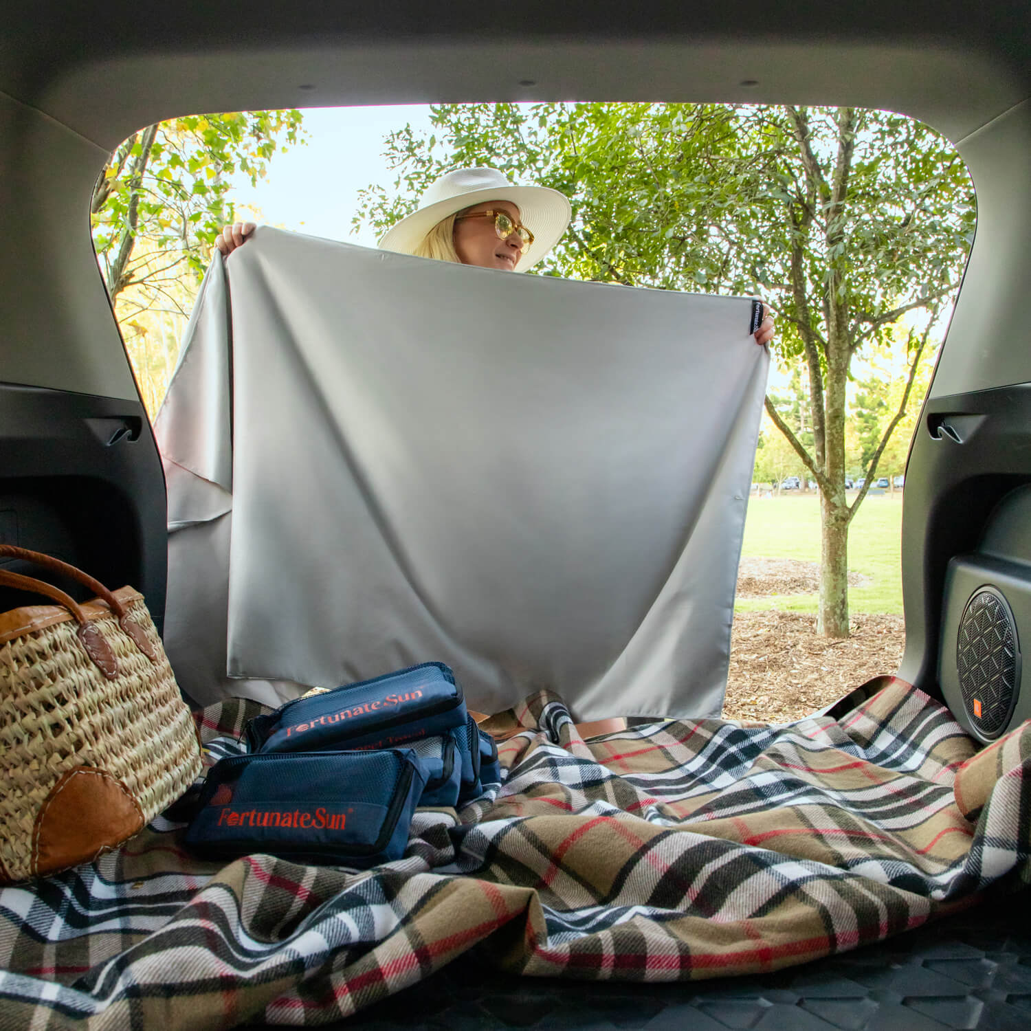 Women hanging up Fortunate Sun Hidey towel in car boot to block out sun.